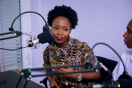 Professional woman sitting behind a studio microphone.
