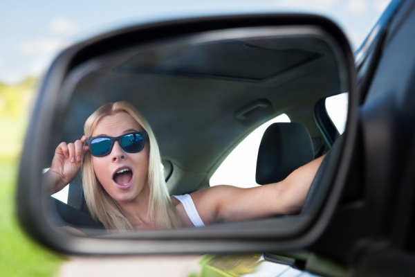 Young blonde woman wearing sunglasses driving car