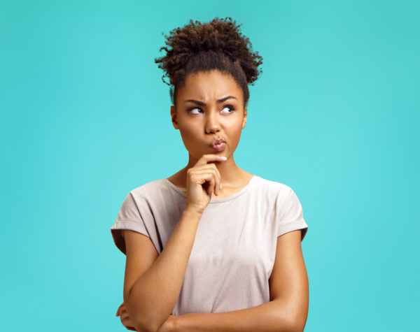 Pensive girl being deep in thoughts, raises eyebrows,