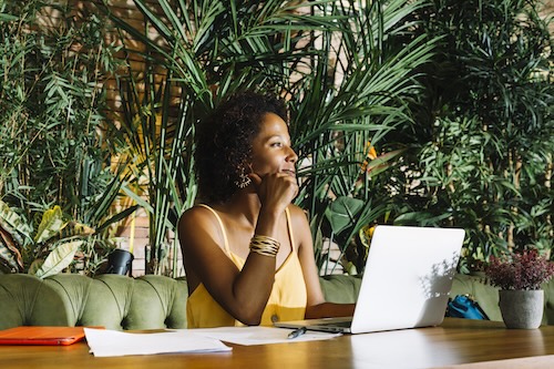 Smiling businesswoman with a laptop, contemplating the business case for her book