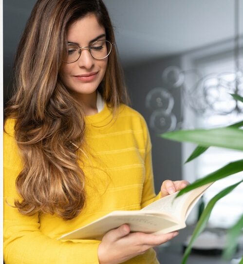 Woman with long hair and glasses reading a book