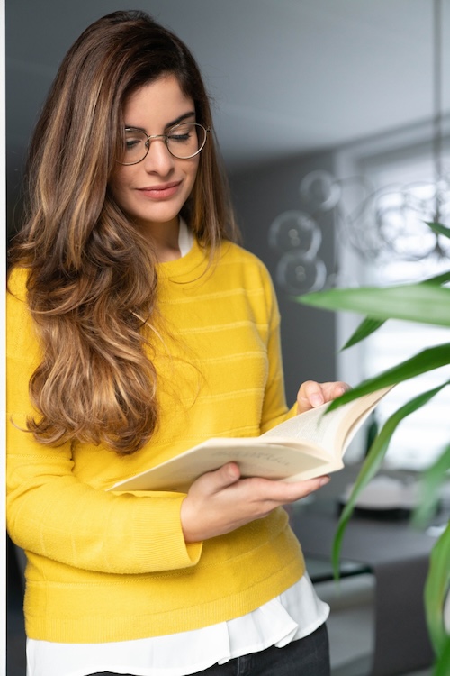 Woman with long hair and glasses reading a book