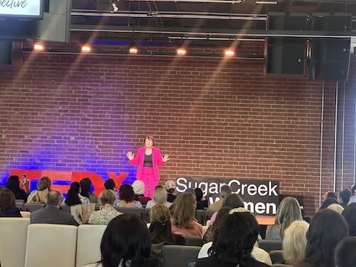 Woman in a pink suit on the TEDx stage