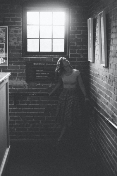 Black and white portrait of Emily with light pouring through window.