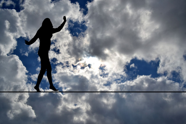 Woman silhouette balancing on rope over blue sky