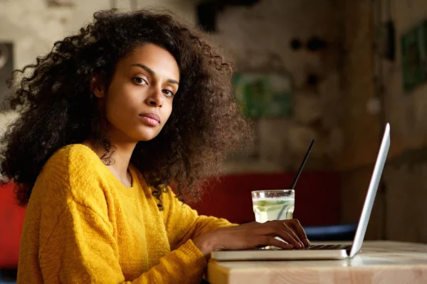 Closeup portrait of serious young african woman working on laptop in a cafe