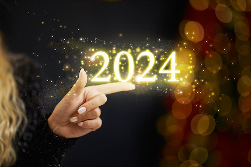 Crop of woman showing at center of golden sparkle description numbers of 2024 New Year. Female in black dress celebrating and pointing by finger on numbers.
